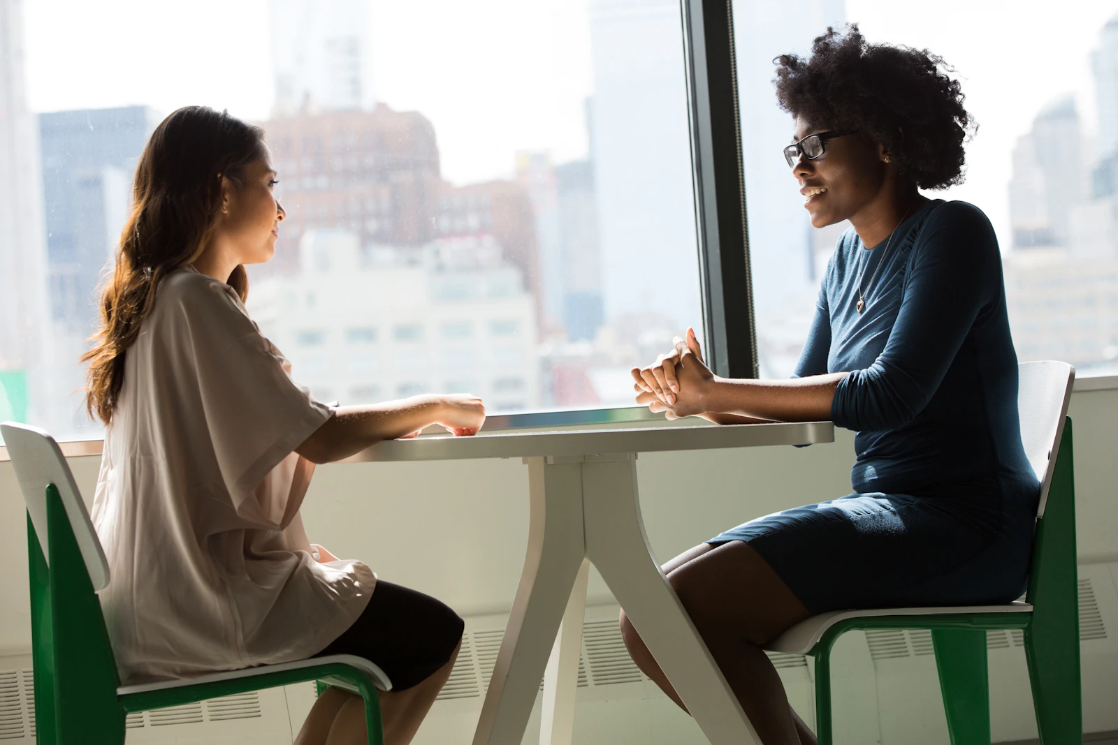 Two professionals in a one-to-one conversation by an office window